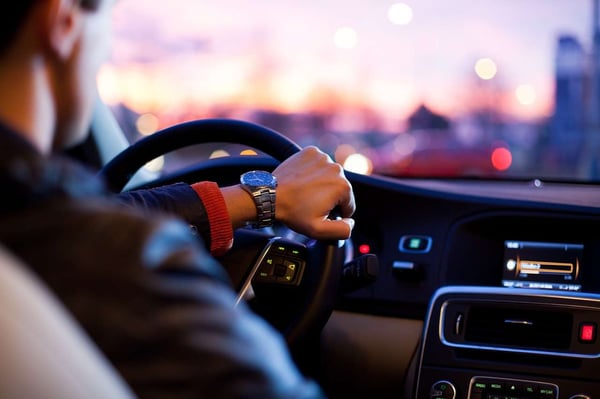 man in leather jacket driving through city at sunset